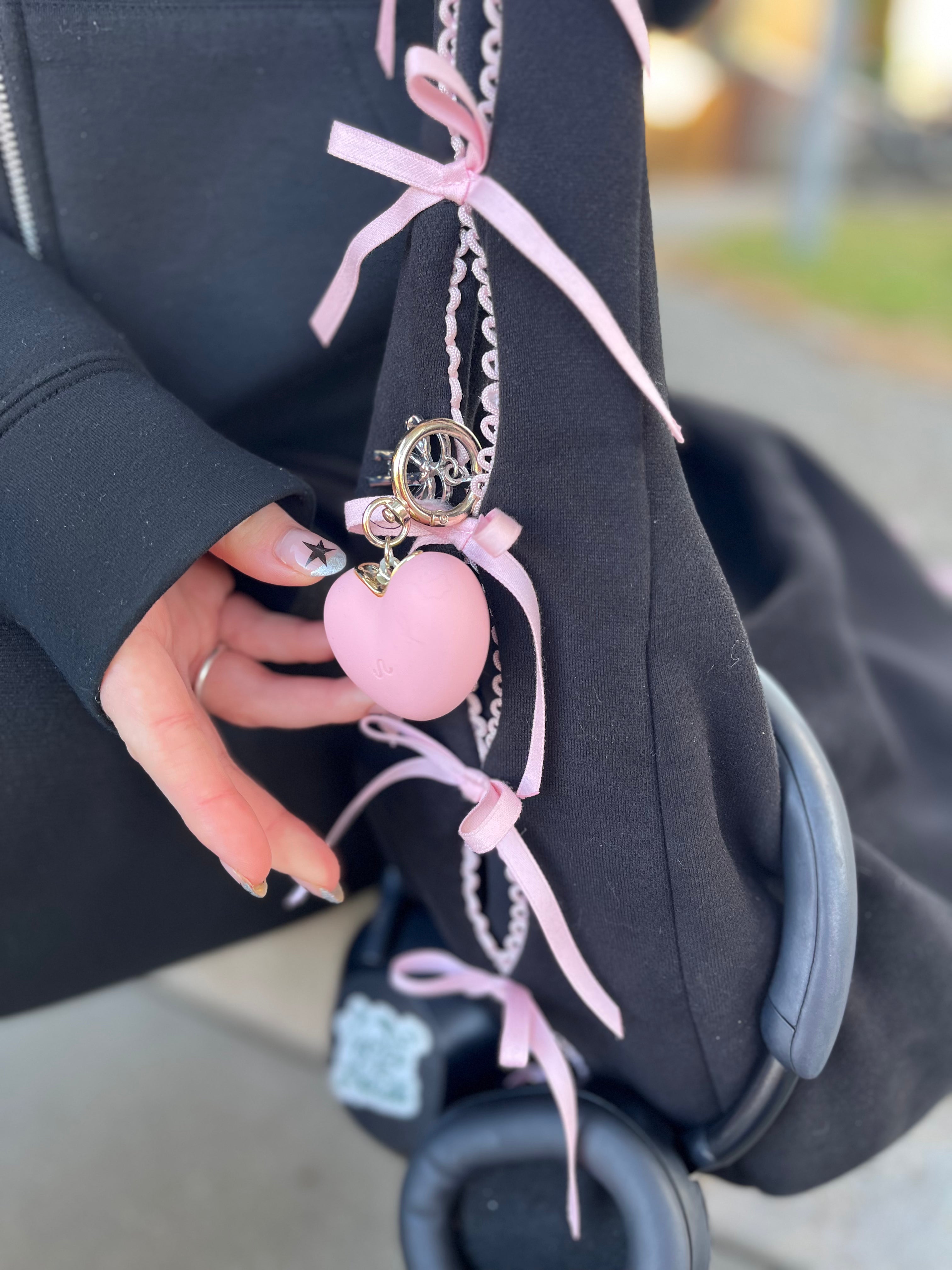 Hjerteformet lyserød tryghedsnøglering i brug på taske 